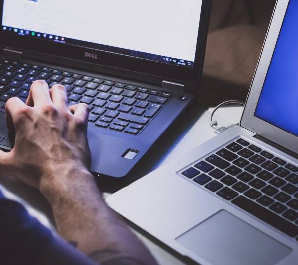 Homme utilisant deux ordinateurs portables